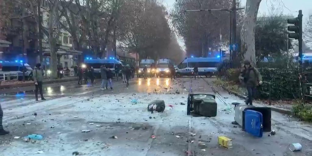 Polizia usa idranti e lacrimogeni contro corteo; manifestanti lanciando pietre e incendi di cassonetti