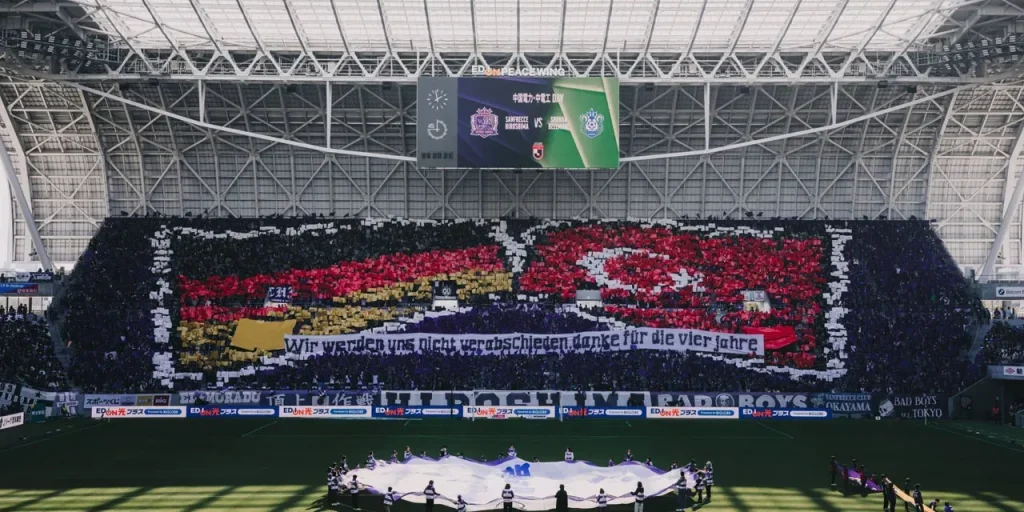 Tifosi di Sanfrecce Hiroshima salutano Skibbe e Umar con coreografia a bandiere tedesche e turche